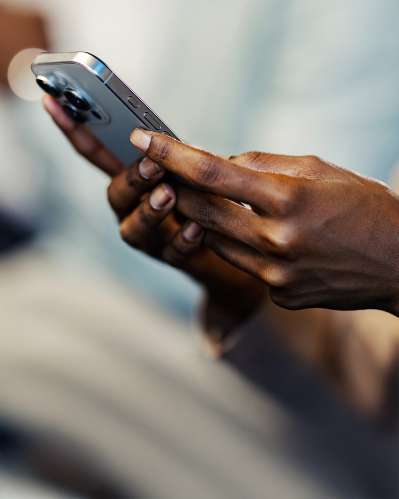 Close-up of a person holding a modern smartphone with both hands, thumbs typing a text message.