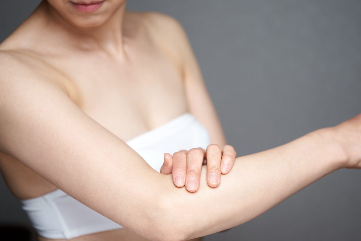 Woman admiring smoother arm skin following CellSound body treatment for improved texture, circulation, & anti-aging results.