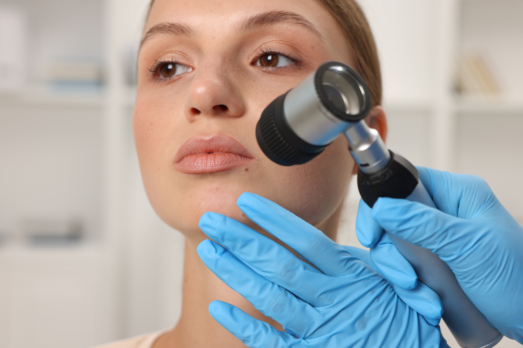 A provider examining a patient's skin with a dermatoscope during a plasma skin regeneration consultation.